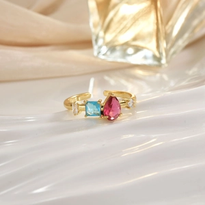 Close-up of golden open ring with pear-cut pink and blue square micro-pave crystals
