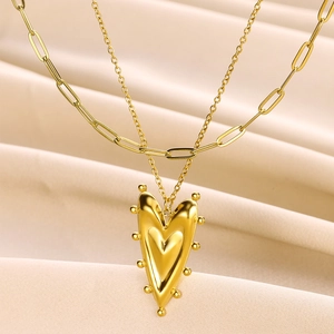 Macro detail of 18K gold stainless steel layered necklace with 3D heart pendant on silk