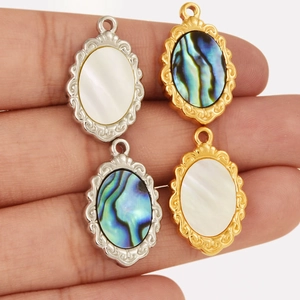 Close-up of vintage oval gold and silver steel pendants with white and abalone shell inlays