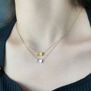 Detail view of gold and silver S925 necklaces with heart letter pendants on a neck