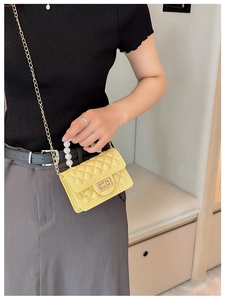 Detail of yellow quilted jelly bag with pearl handle and golden chain shoulder strap