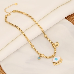 Detail view of gold snake chain necklace with evil eye pendant and fringe accents