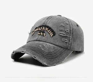 Detail of distressed dark grey denim baseball cap with vintage embroidery and worn texture
