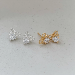 Macro shot of silver and gold bow earrings with sparkling round cubic zirconia inlay