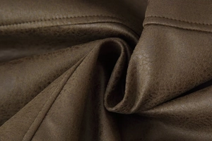 Detailed macro view of vintage dark brown faux leather texture with soft natural creases