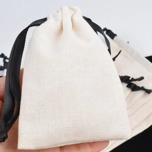 Close-up of beige cotton linen drawstring jewelry bag held by hand for packaging
