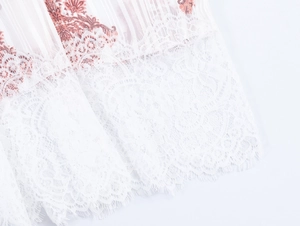 Dettaglio dell'abito boho con orlo in pizzo bianco e tessuto con stampa rosso-marrone