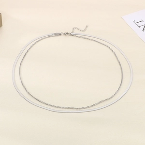 Detail of silver double-layered necklace featuring a thin chain and wide snake chain link