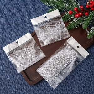 Clear acrylic Christmas ornaments set with snowflake and icicle shapes on wooden tray