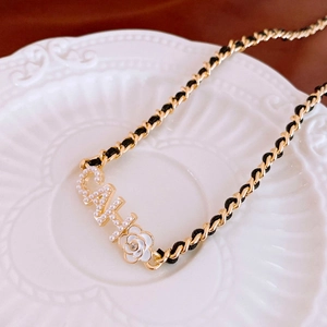 Detail of woven chain necklace with pearl-inlaid letters and white camellia flower
