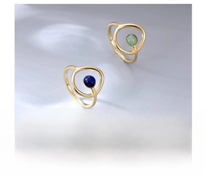 Vista detallada de anillos de acero de titanio dorados con gemas azules y verdes incrustadas