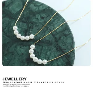 Close-up of gold beaded pearl necklace on deep green marble tray showing fine texture