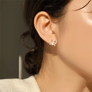 Close-up of heart-shaped twisted knot stud earrings worn on model for a stylish look