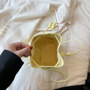 Mini yellow woven bucket bag with drawstring closure and slim leather shoulder strap