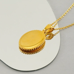 Fashionable gold oval religious pendant necklace in stainless steel on a mirrored surface