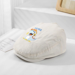 Detailopname van beige kinderbaret met geborduurde dinosaurus en fijne textuur
