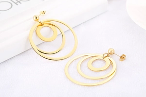 Close-up of golden triple-layered geometric hoop earrings with polished metallic finish