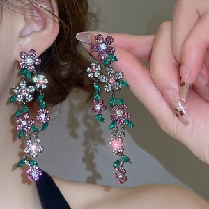 Close-up of sparkling floral tassel earrings with pink crystals and long fringe detail