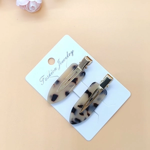 Close-up of a pair of tortoiseshell acetate hair clips on a white paper card
