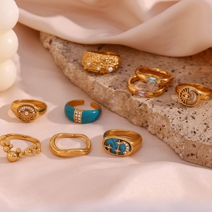 Detail of 18K gold plated rings with turquoise enamel and zircon inlays on silk