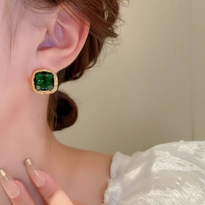 Close-up of vintage emerald green square stud earrings with gold plating on model's ear