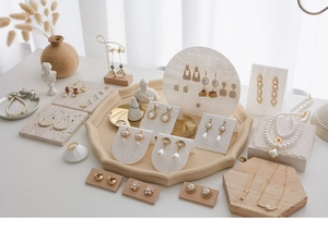 Detailed display of pearl earrings and gold necklaces on marble acrylic jewelry stands