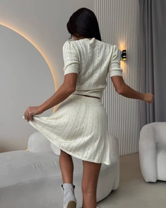 Gros plan détaillé d'un ensemble en maille crème montrant des motifs ajourés délicats