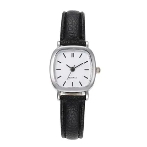 Close-up of a square silver watch with a white dial and black leather strap in minimalist style