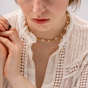 Close-up of a necklace with colorful crystal beads and white pearls on a model's neck