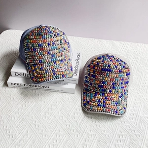Detailed view of colorful pearls and rhinestones on light blue and beige baseball caps