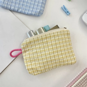 Macro shot of yellow checkered pouch containing cosmetics on a clean white desk