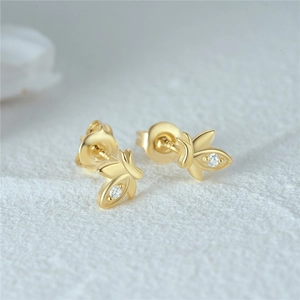 Macro view of gold flower earrings with a central diamond and secure butterfly backs