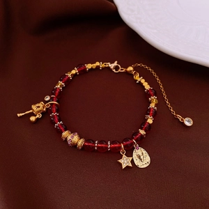 Detailed shot of dark red beaded bracelet with gold religious coin and star pendants