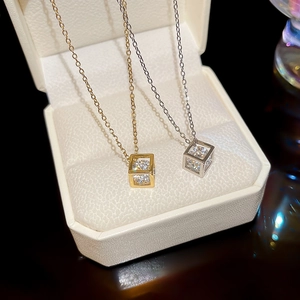 Macro detail of gold and silver hollow cube pendants with cubic zirconia on fine chains