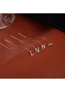 Detailed close-up of silver letter pendants L N W I on a premium brown leather background