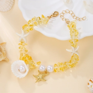 Detail of bohemian ocean bracelet with yellow gravel, white pearls and gold starfish charm