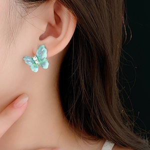 Détail de la boucle d'oreille papillon vintage avec strass et dégradé bleu sur modèle