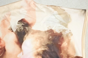 Close-up of beige sleeveless top featuring vintage angel print and fine seam stitching