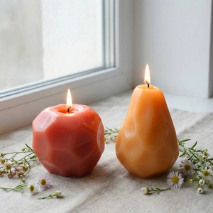Geometric apple and pear scented candles on linen cloth with dried daisy accents