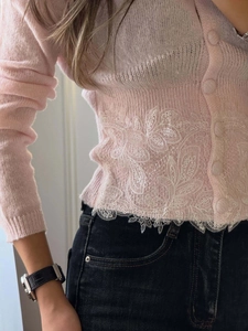 Detail der rosa Strickjacke mit zarter weißer floraler Spitzenstickerei am Saum