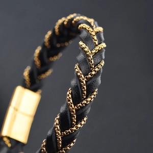 Macro detail of black braided leather bracelet with golden chain and magnetic clasp