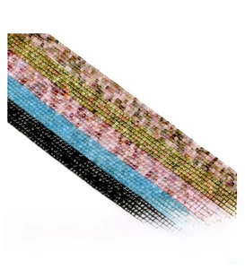 Macro shot of 2.5mm square crystal beads in pastel green, sky blue, and black tones