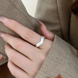 Close-up of matte silver wavy ring with freedom engraving worn on model's hand