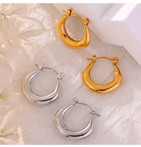 Gros plan artistique de boucles d'oreilles en U en acier doré et argenté sur texture