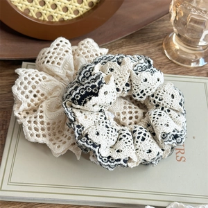 Detailed view of layered lace scrunchies in cream and black on vintage book background