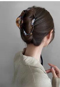 Detail view of large amber resin hair claw clip holding a secure bun on a model