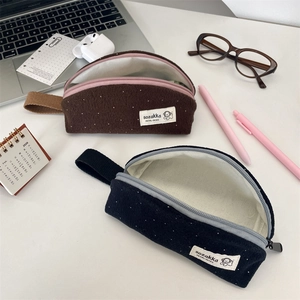 Close-up of wool felt polka dot pencil cases with zippers and wrist straps on a desk