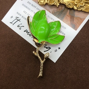 Macro detail of magnolia bud brooch with green enamel and textured gold branch