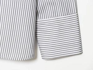Détail des poignets et de l'ourlet sur une chemise en popeline à rayures fines et coutures