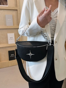 Detail of black lychee leather crescent bag featuring silver star and chain strap